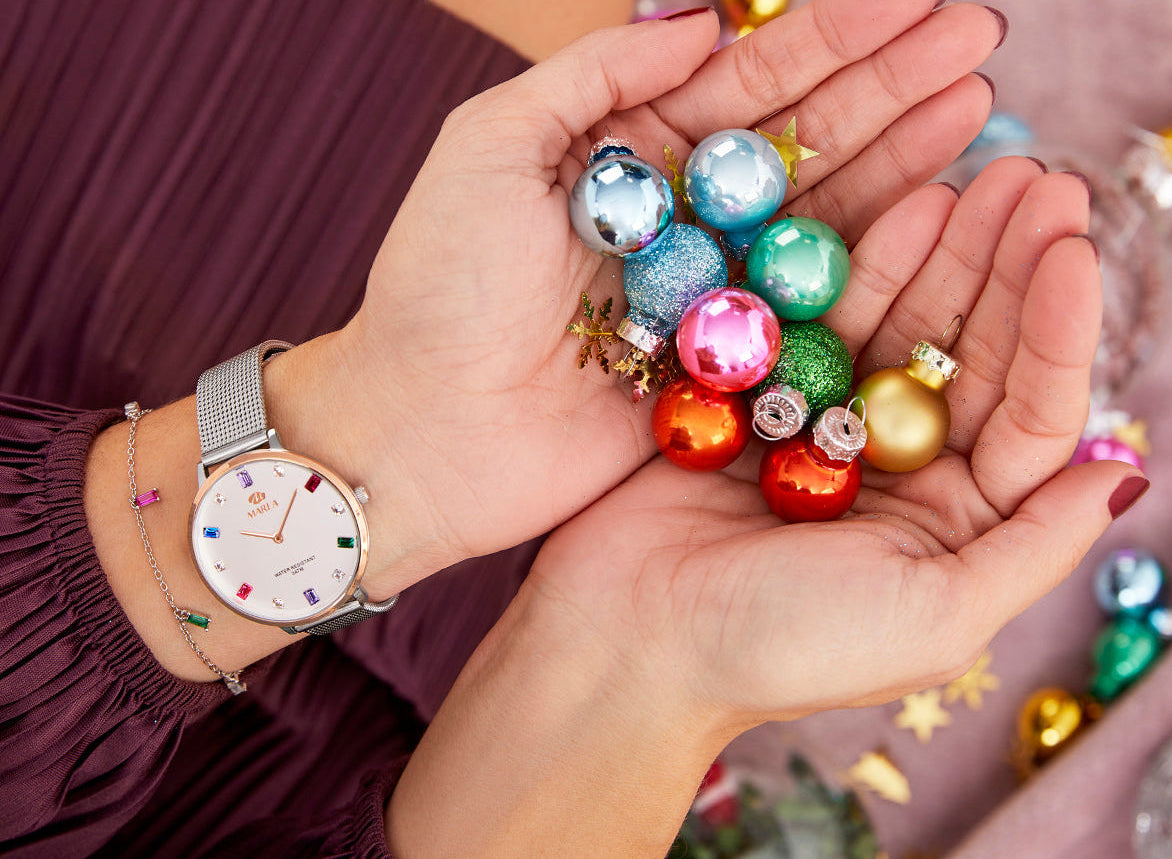 Person holding colorful miniature ornaments in their hands with a Marea watch on their wrist.